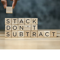 Hand stacking blocks that reads "stack don't subtract"