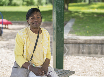 Smiling Elaine sitting on park bench