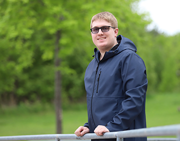 Graham smiling and leaning against a railing