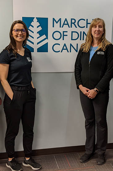 Two smiling MODC staff standing in front of an MODC logo sign
