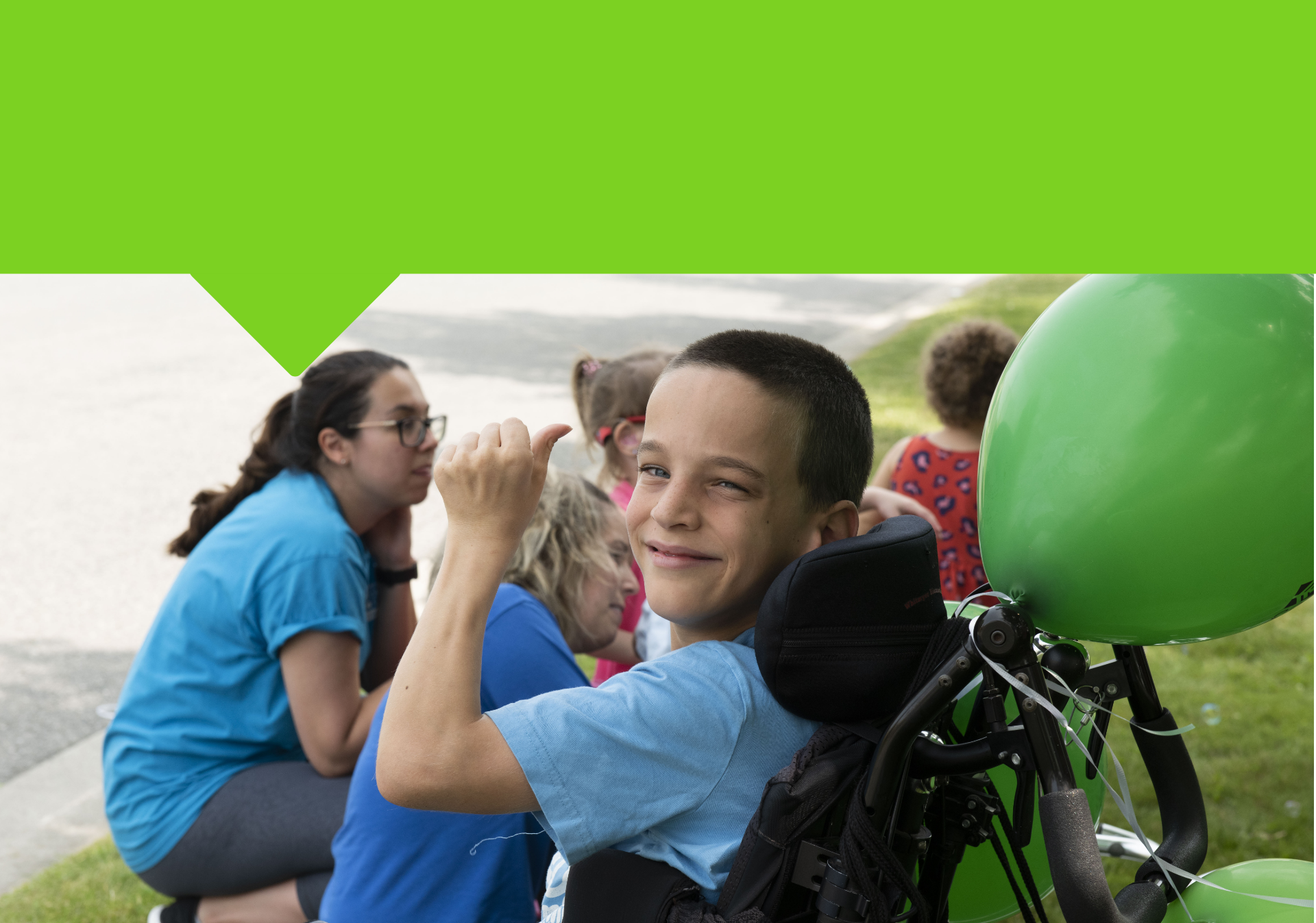 Smiling child in a wheelchair giving a thumbs up