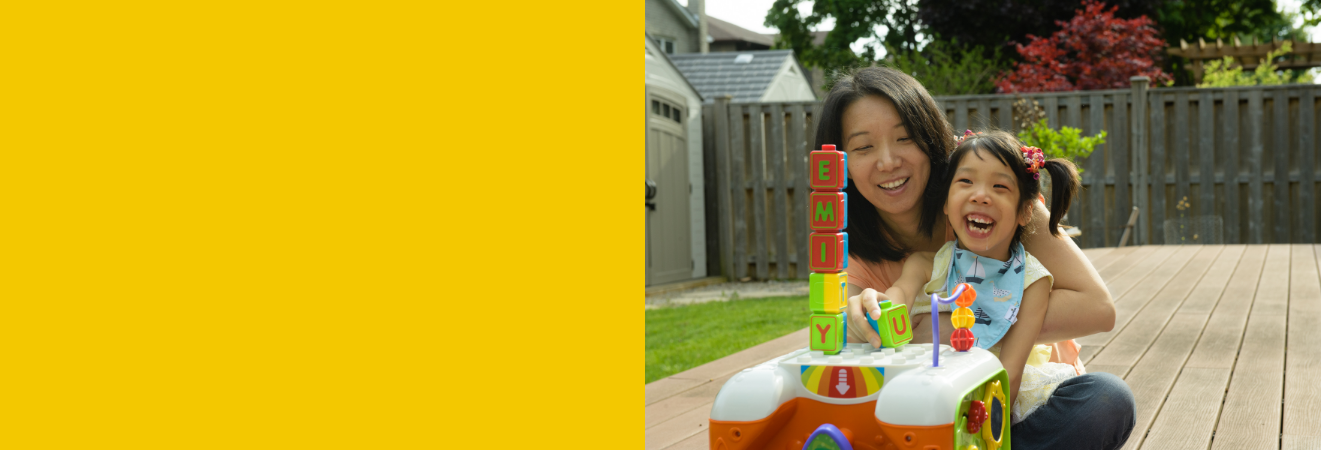 Smiling Emily and mother playing with blocks on a porch