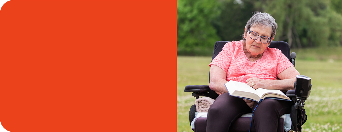 Rose sitting in her wheelchair outside reading a book