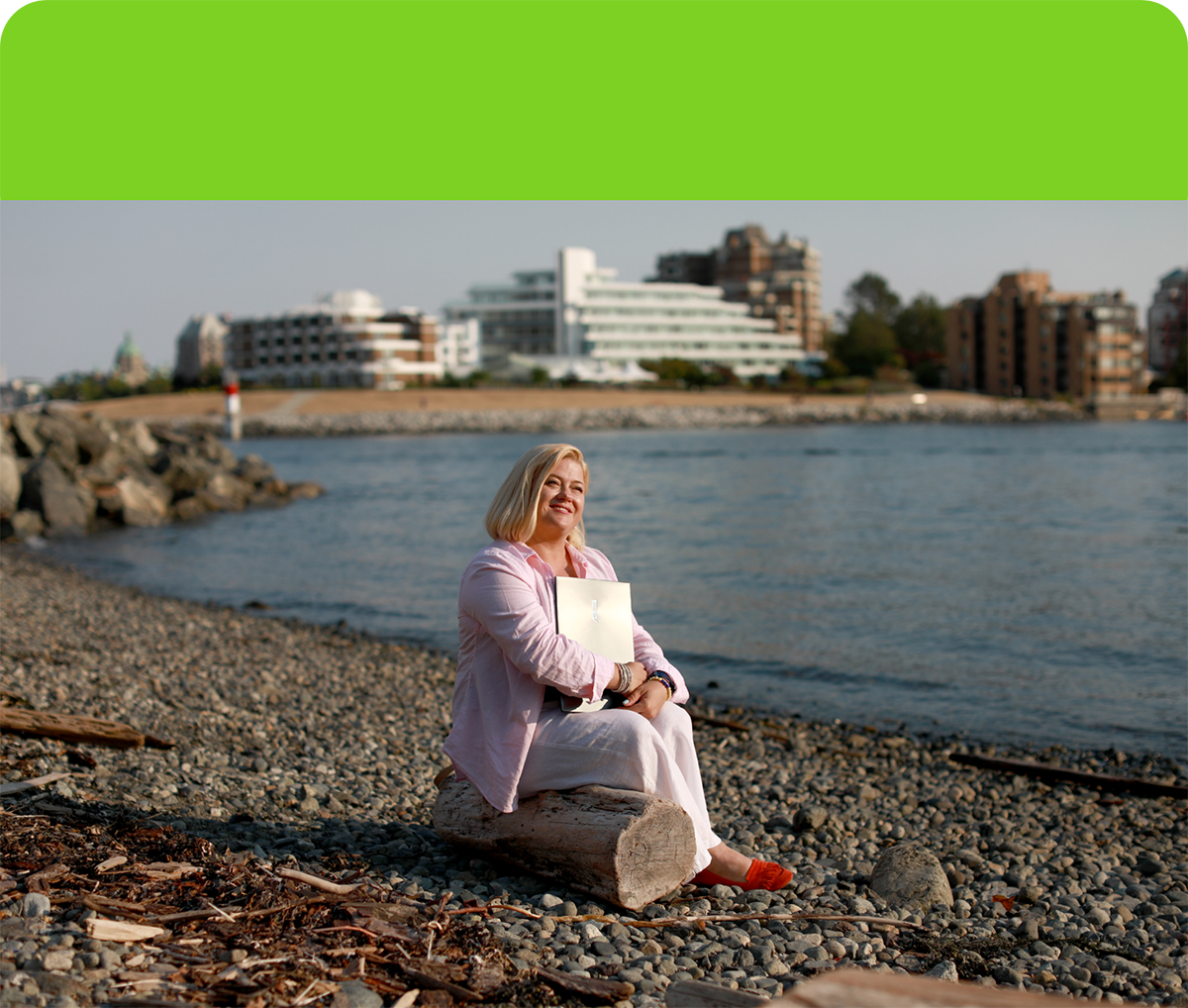 Liubov Moisieieva sitting on a beach holding her laptop