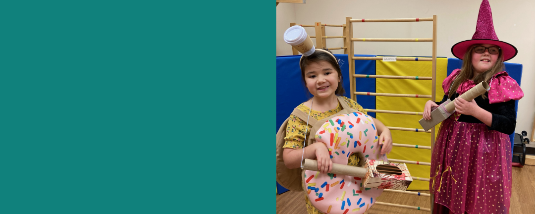 Two CE kids smiling and dressed up for halloween as a spinkled donut and a witch in pink pointed hat