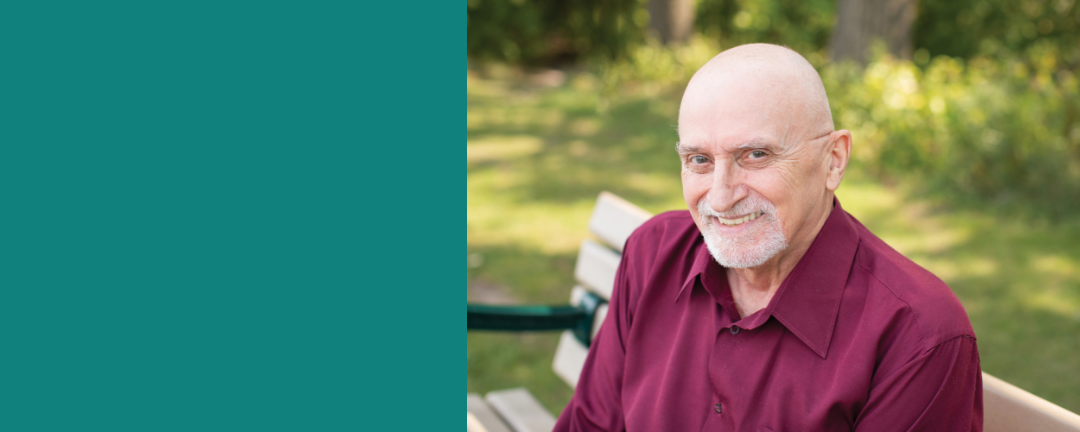 Smiling service user Ron La Combe sitting on a park bench