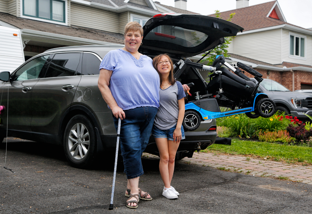 Smiling HVMP service user hugging her daughter in front of her modified car