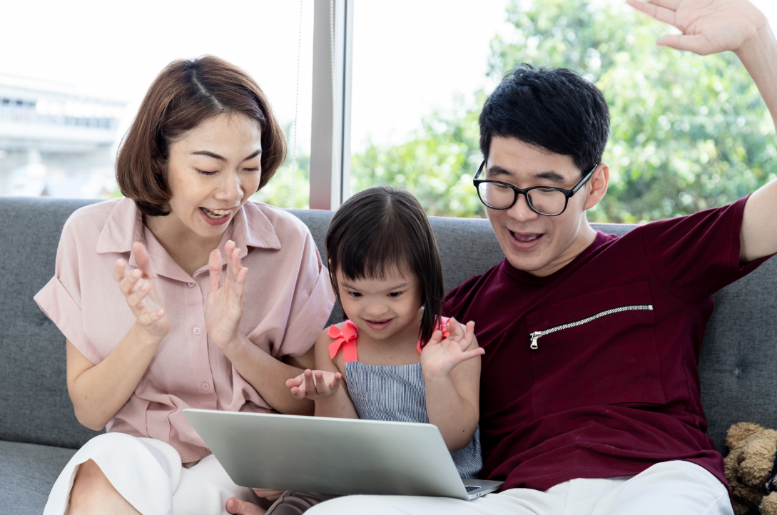 Parents sitting with their child with disabilities cheering while watching a laptop screen