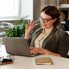 Woman waving at her laptop while on a webinar