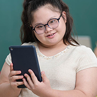 Girl with glasses in white top holding a grey tablet
