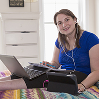 Smiling young woman working on laptop and tablet