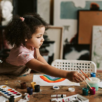Child painting a rainbow in an art class.